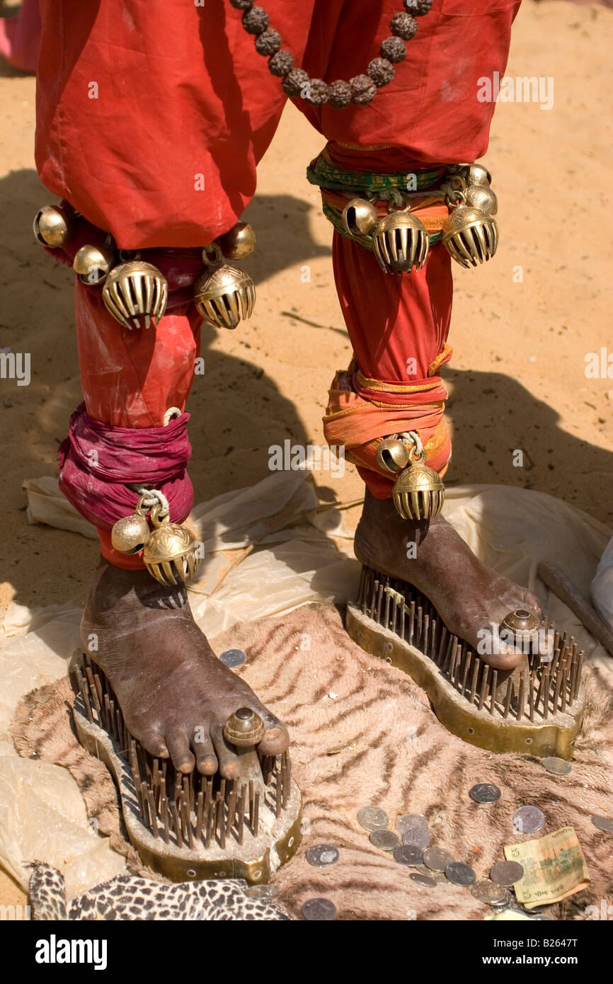 Ein Sadhu steht unter einem Sonnenschirm auf Schuhe von Nägeln bei Talakkad in Karnataka stehend. Stockfoto