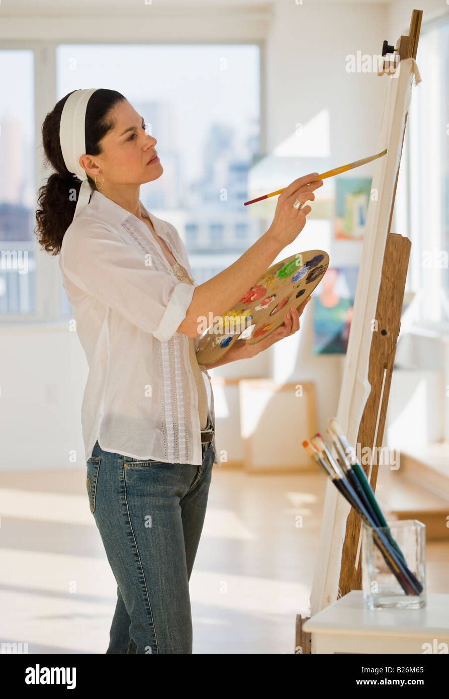 Hispanic Frau malt auf Staffelei Stockfoto