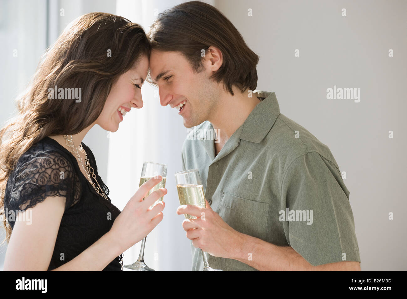 Paar mit Champagner und Stirnen berühren Stockfoto