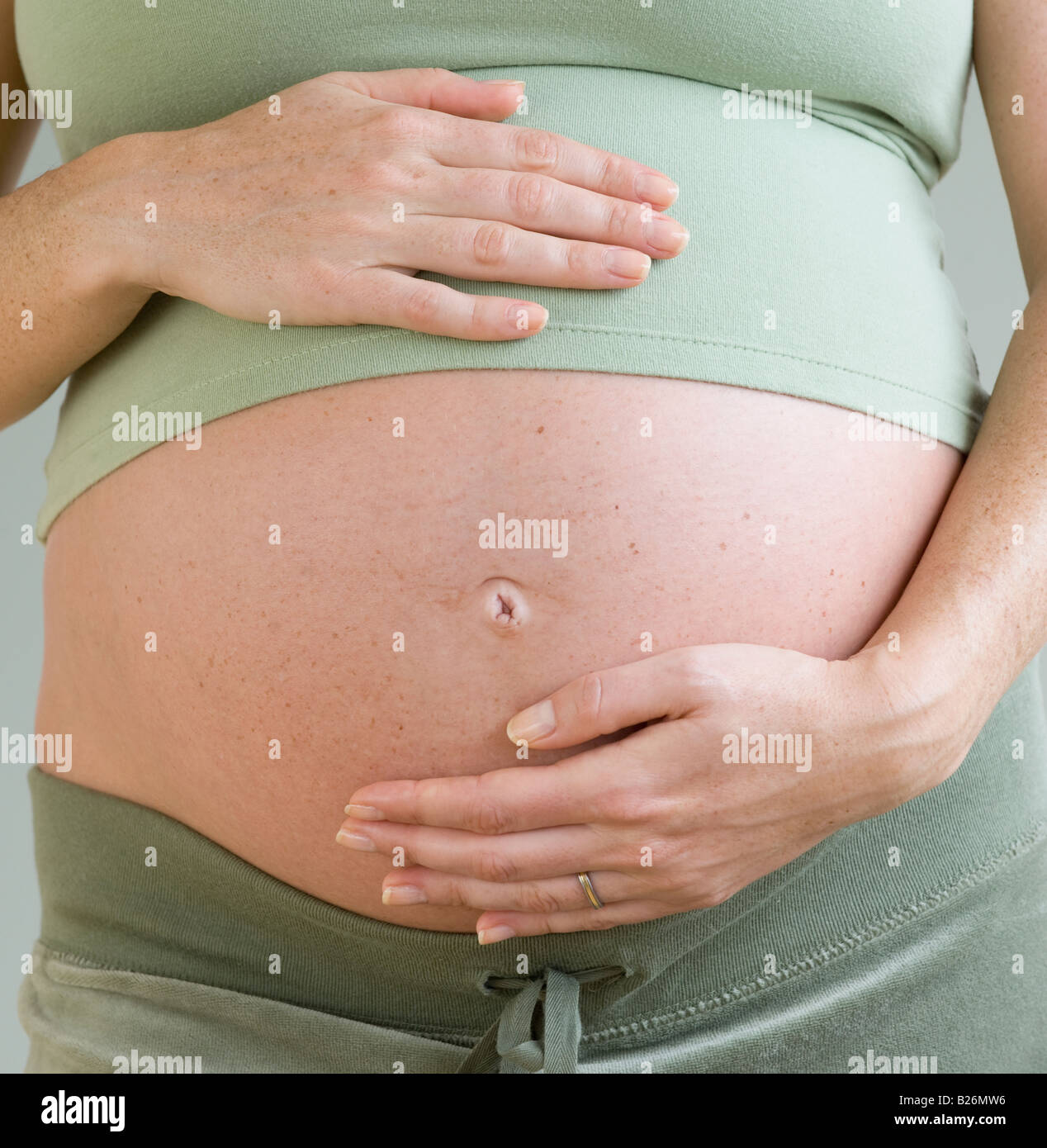 Schwangere Frau mit Händen am Bauch Stockfoto