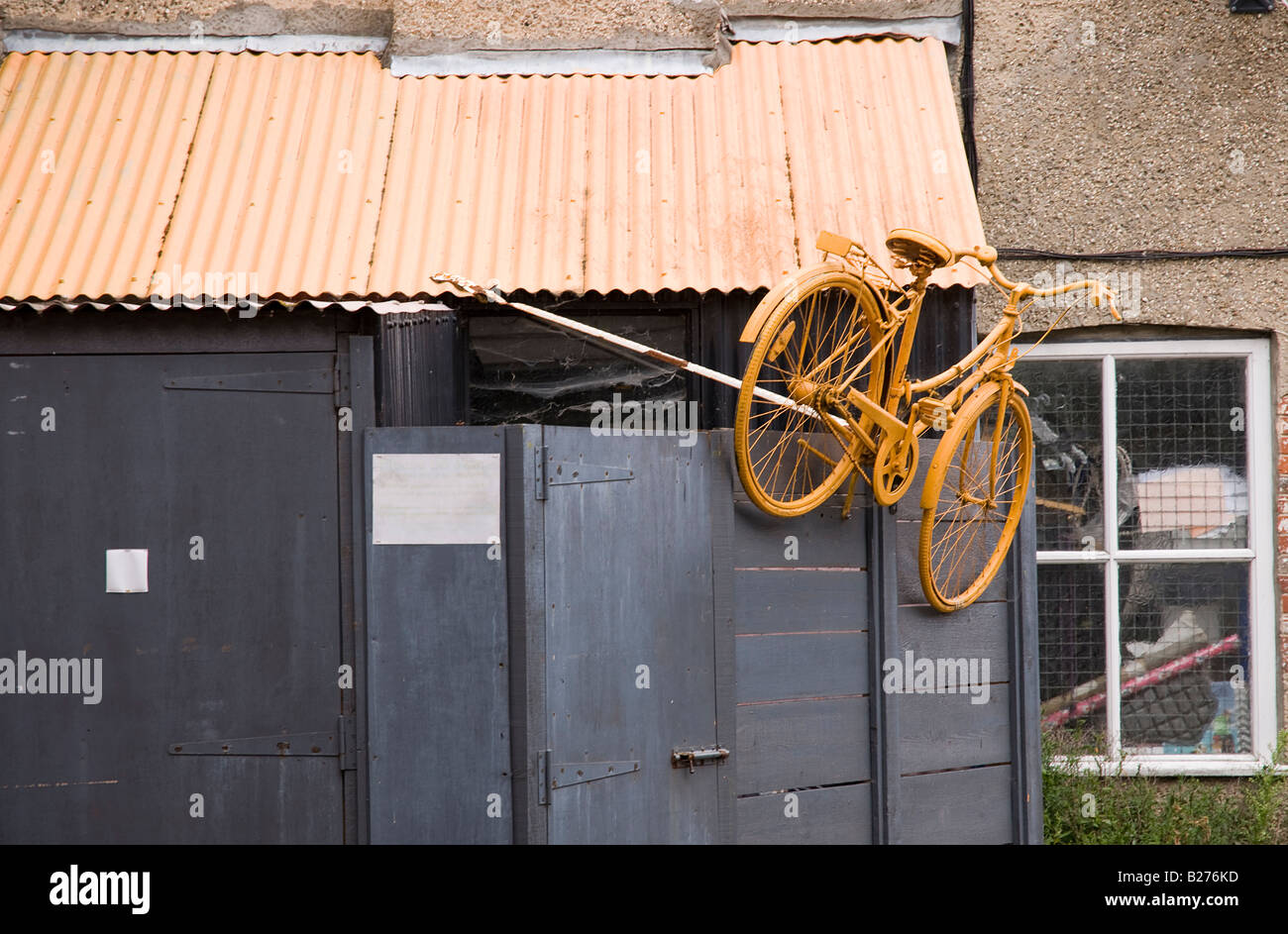 Ein Fahrrad helles Gelb lackiert und seitlich an einem Schuppen eine Zyklus-Werkstatt Stockfoto