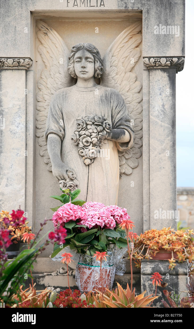 Eine steinerne Statue eines Engels und einige Blumen schmücken ein Familiengrab, Mallorca, Spanien. Stockfoto