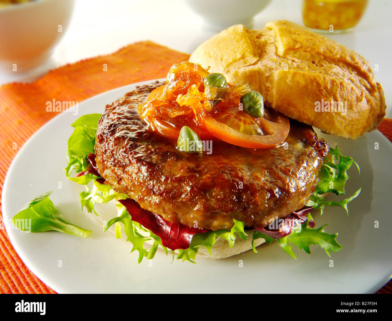 Bio-Rindfleisch-Burger mit Tomaten-Relish und Salat in einem Brötchen Stockfoto