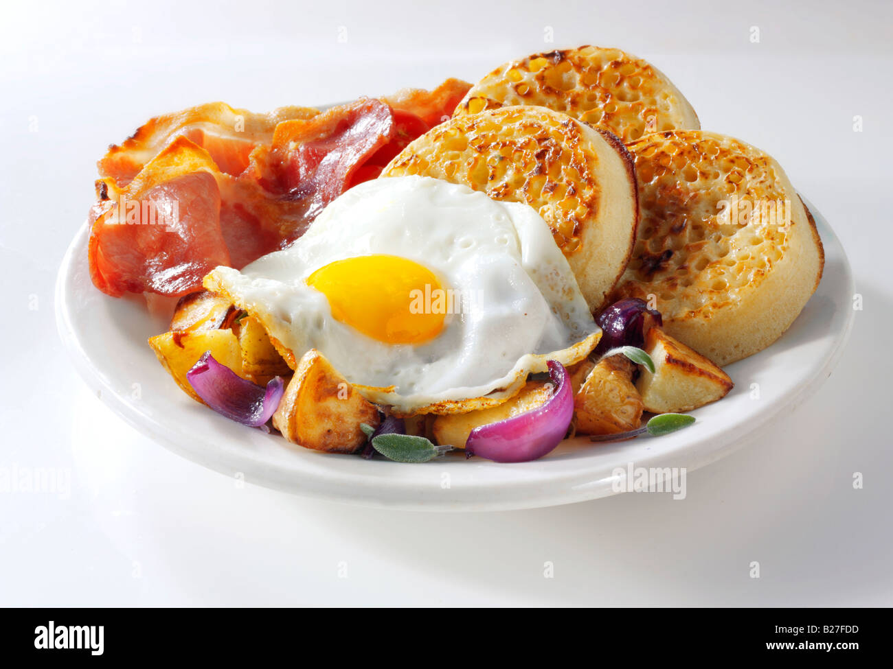 Englisches Frühstück mit Gipfeli, serviert auf einem weißen Teller in einer Tabelle einstellen - Spiegelei, Speck, Bratkartoffeln und Gipfeli Stockfoto