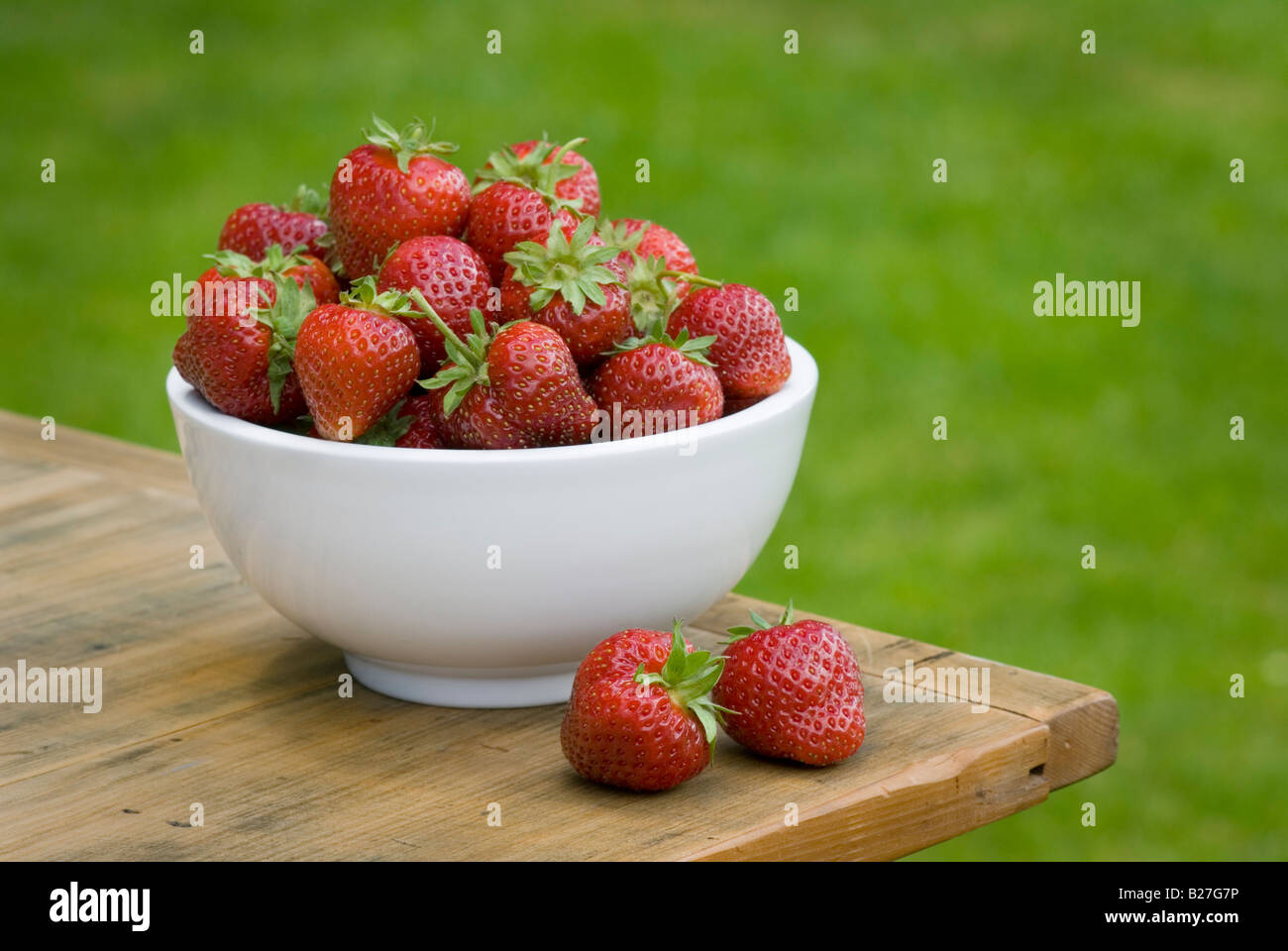 Eine Schüssel mit frisch gepflückten Erdbeeren auf einem Holztisch außerhalb Stockfoto
