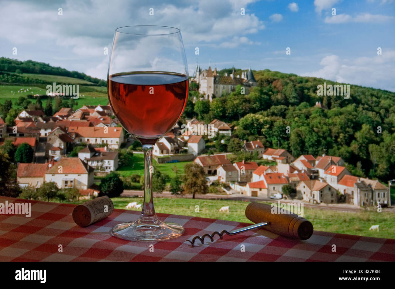 Roséwein im Freien, Picknick mit Weinprobe auf einer typischen französischen Tischdecke mit kariertem Glas, mit Dorf und Chateau de la Rochepot hinter Burgund Frankreich Stockfoto