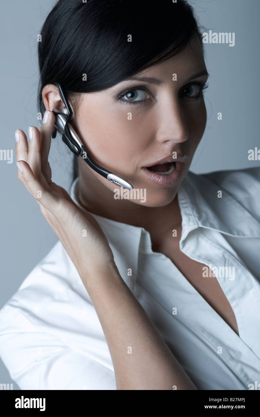 Schöne Brünette Geschäftsfrau mit drahtlosen Kopfhörer auf hellen Hintergrund isoliert Stockfoto