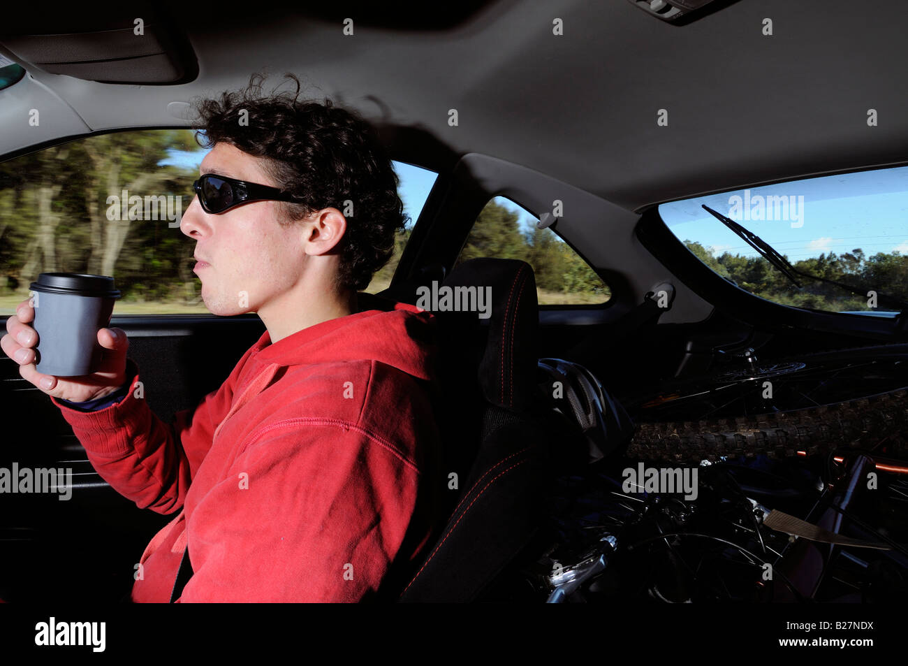 Mann, Kaffee zu trinken, beim Auto fahren Stockfoto