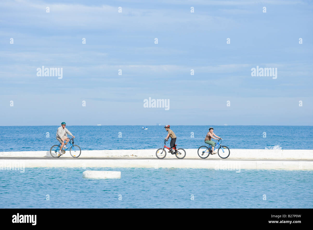 Newcastle, New South Wales, Australien. Vater mit Sohn und Tochter auf ihren Fahrrädern entlang der Kante der historischen Ocean Bäder. Stockfoto