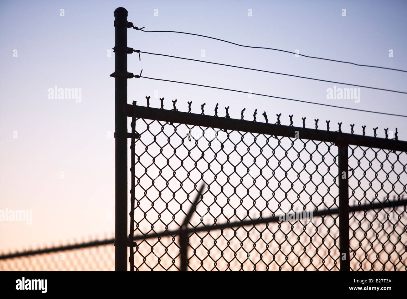 Silhouette von Stacheldraht und Maschendrahtzaun Stockfoto