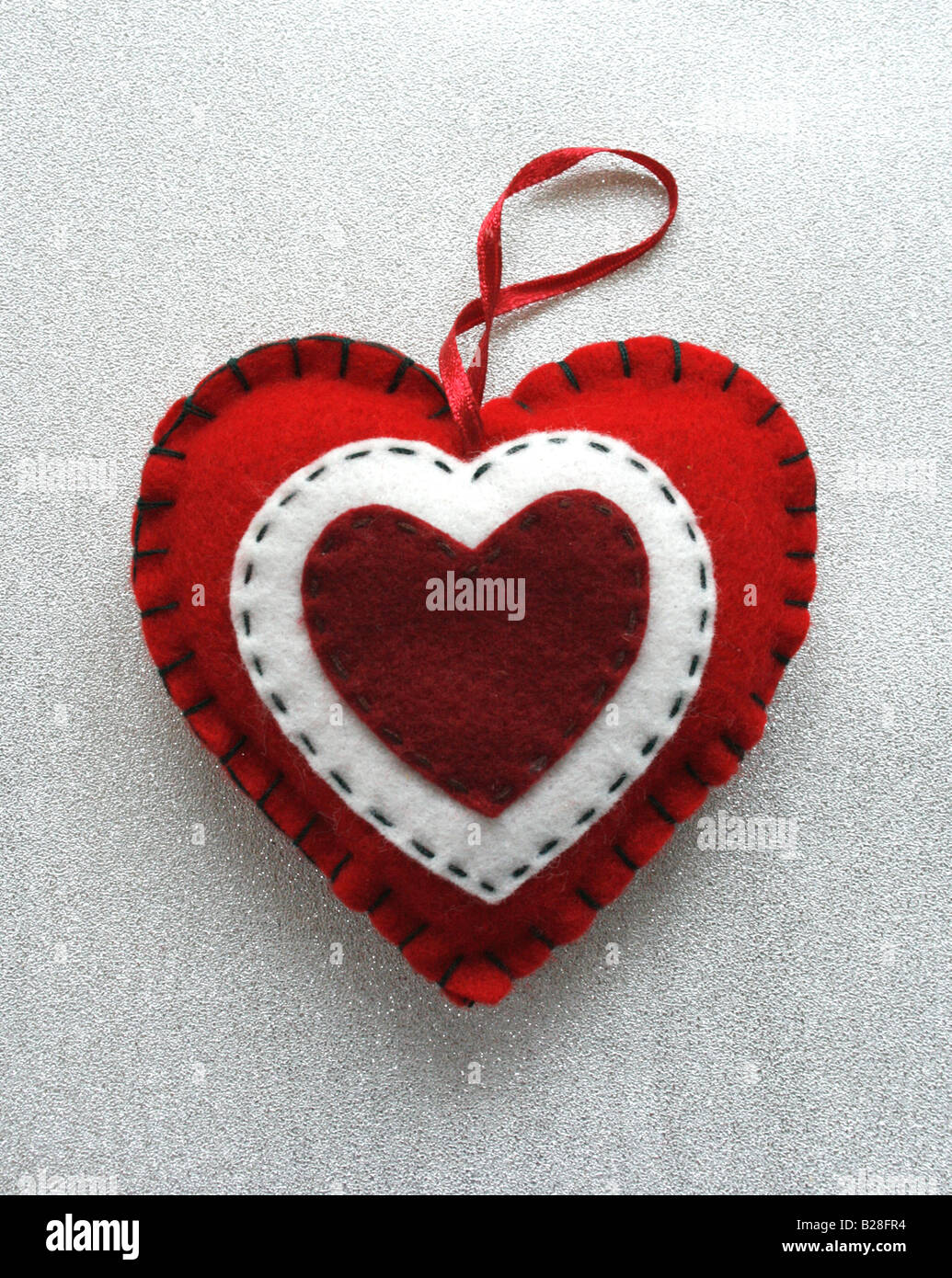 Weihnachten / Valentinstag: ein rot-weißes fühlte Herz auf Silber. Stockfoto