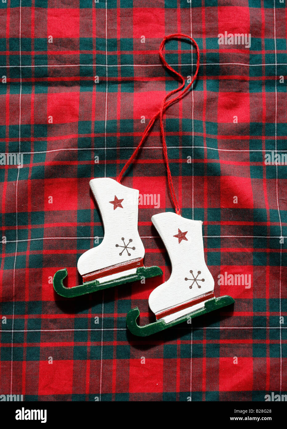 Weihnachten: Aus Holz gemalte Schlittschuhe auf Tartan Stoff Hintergrund.  (Foto-Extras) Stockfoto