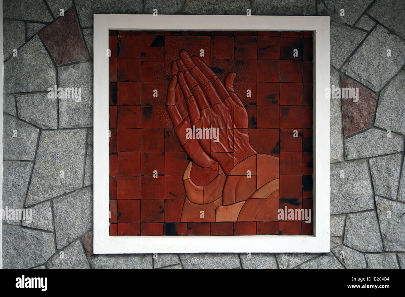 Skulptur von Palmen trat im Gebet wie in einen Bilderrahmen, ein Wandgemälde auf die Steinwand einer Kirche darzustellen Stockfoto