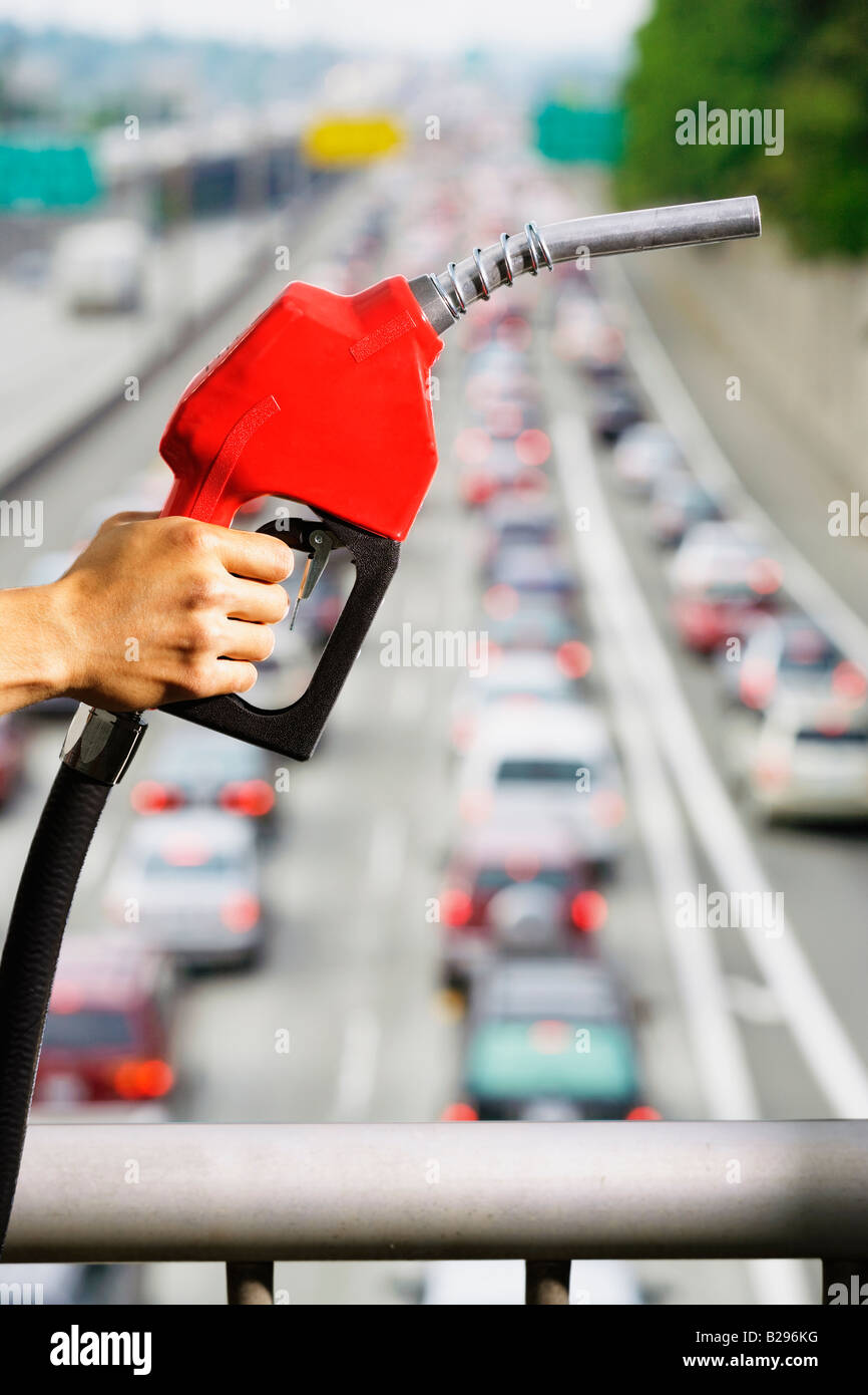 Eine Hand hält eine Gas Pumpe Nozzlein Front der Autobahnverkehr Stockfoto