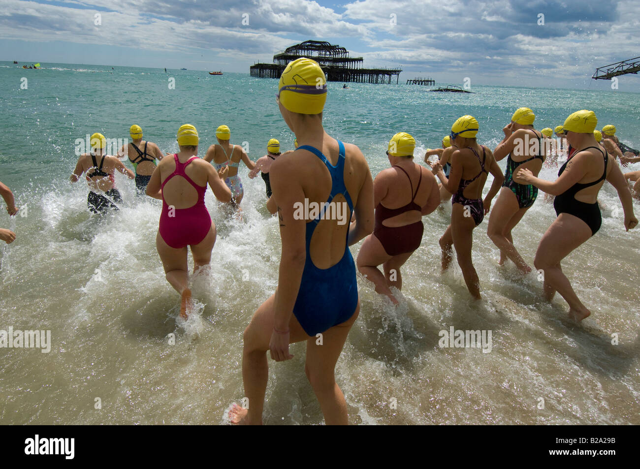 Weibliche Schwimmer stürzen ins Meer in Brighton für das jährliche Pier, Pier-Rennen. Stockfoto