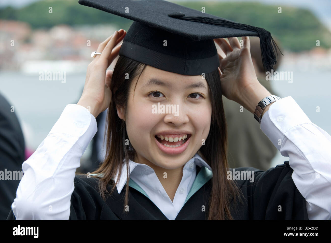 Eine asiatische Studentin passt ihren Doktorhut vor einem Abschluss-Zeremonie Stockfoto