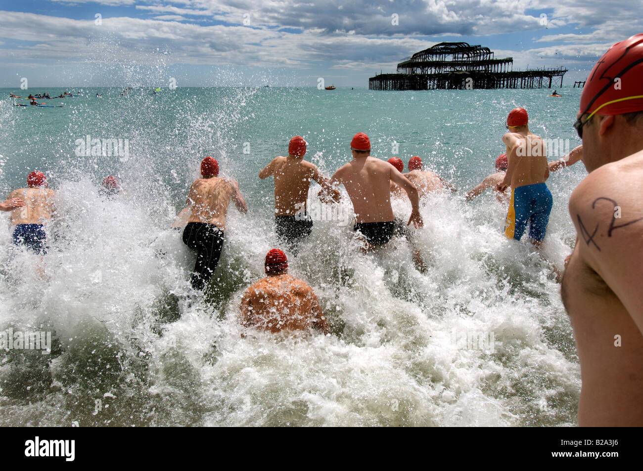 Männliche Schwimmer stürzen sich in das Meer in Brighton für das jährliche Pier, Pier-Rennen. Stockfoto