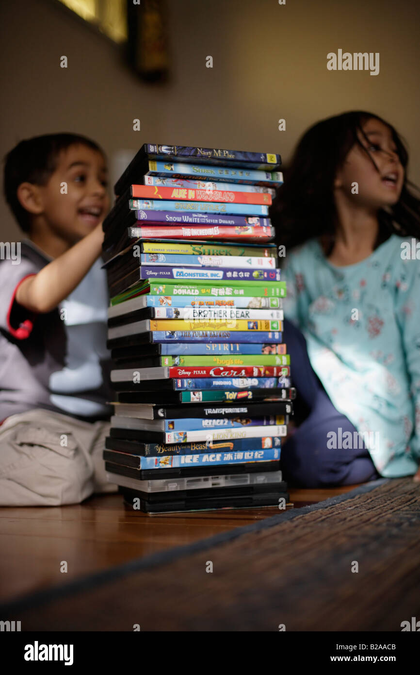 Bruder betrachten im Alter von sechs und Schwester fünf ihre DVD Sammlung Mischlinge indischen ethnischen und kaukasischen Stockfoto