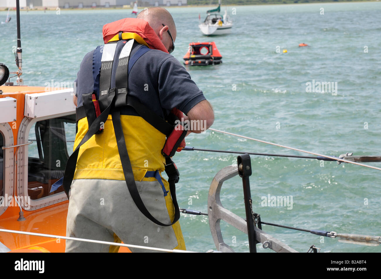 Ein Crew-Mitglied dons eine Schwimmweste, denn das Rettungsboot unterlegten besuchen soll Stockfoto