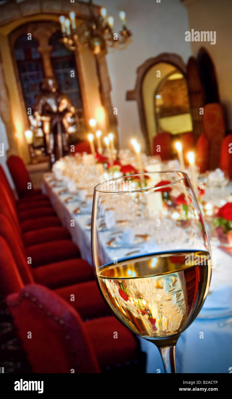 Weißweinglas im Vordergrund eines formell vorbereiteten, luxuriösen Dinner-Bankett-Partytisches bei Kerzenschein. Weinprobe Stockfoto