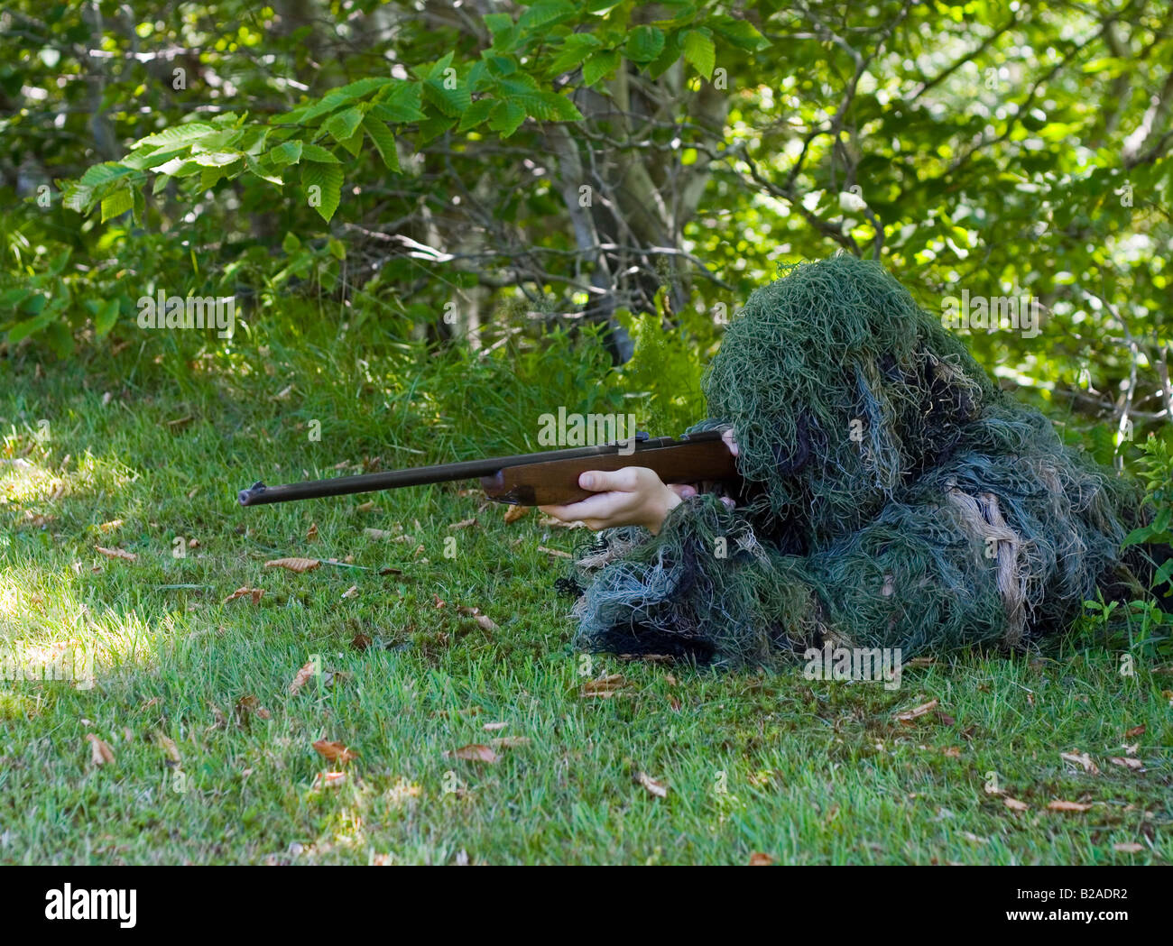 Scharfschütze im Ghillie Anzug mit.22 Kaliber Gewehr mit dem Ziel Sie Rahmen Stockfoto
