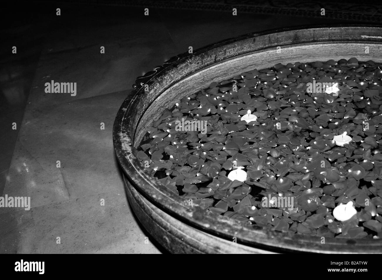 Schwarz / weiß Aufnahme von Rosenblüten und Kerze in Kupfer Cotainer schweben Stockfoto