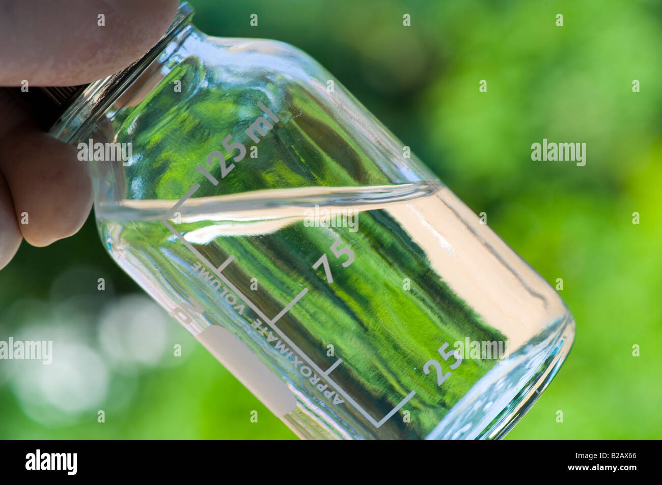 Hand, die kleines Fläschchen klare Flüssigkeit im freien Stockfoto