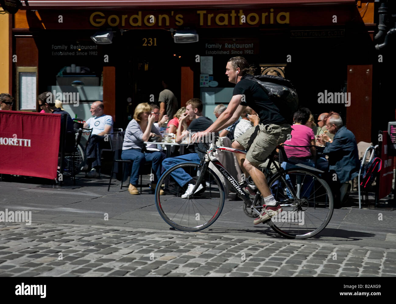 Männliche Radfahrer Radsport auf gepflasterten Straße vorbei an Restaurant, High Street, Royal Mile Edinburgh, Schottland, UK, Europa Stockfoto
