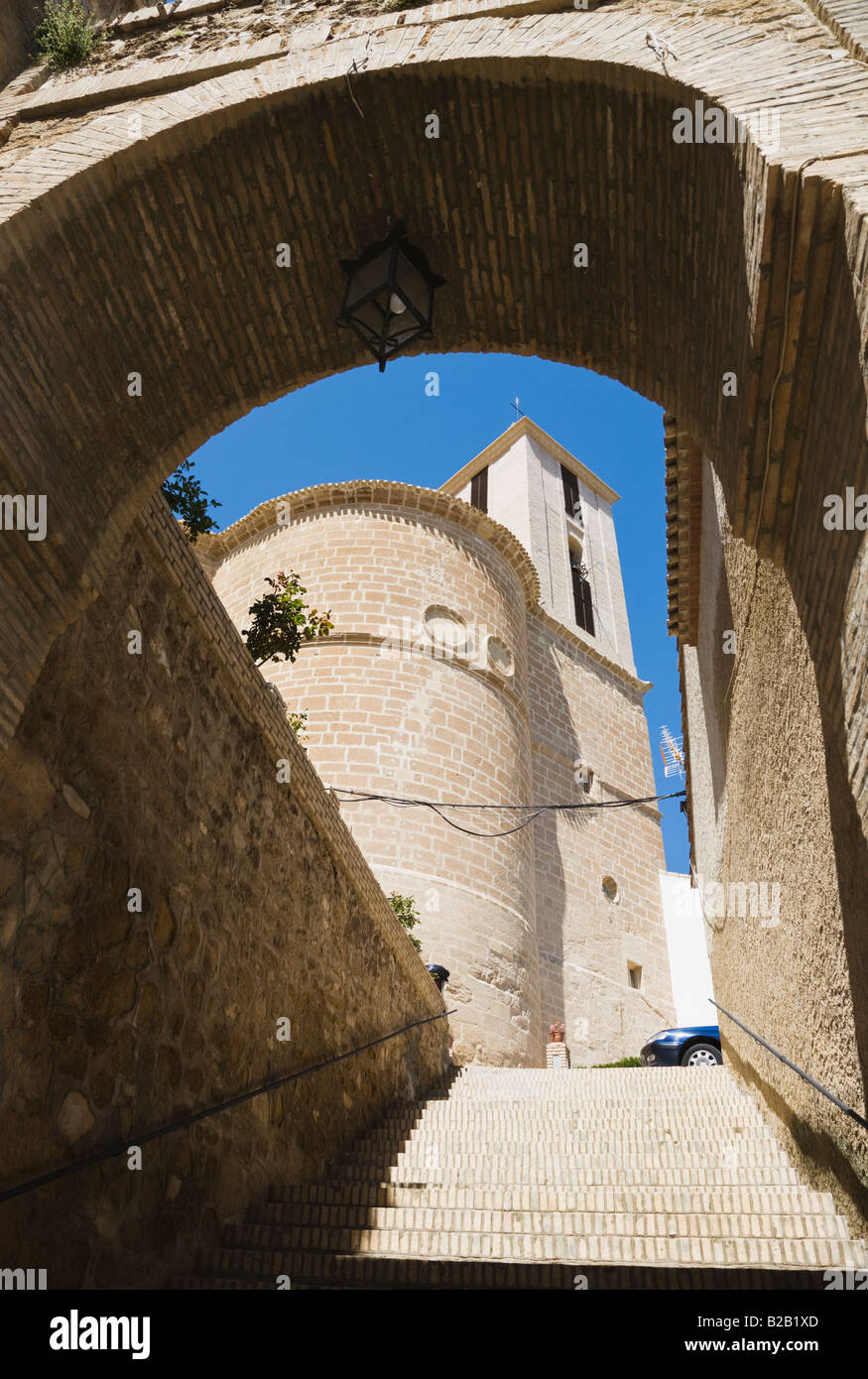 Iznajar Granada Provinz Spanien Iglesia Parroquial de Santiago Apóstol durch Bogen der mittelalterlichen Stadtmauer zu sehen Stockfoto