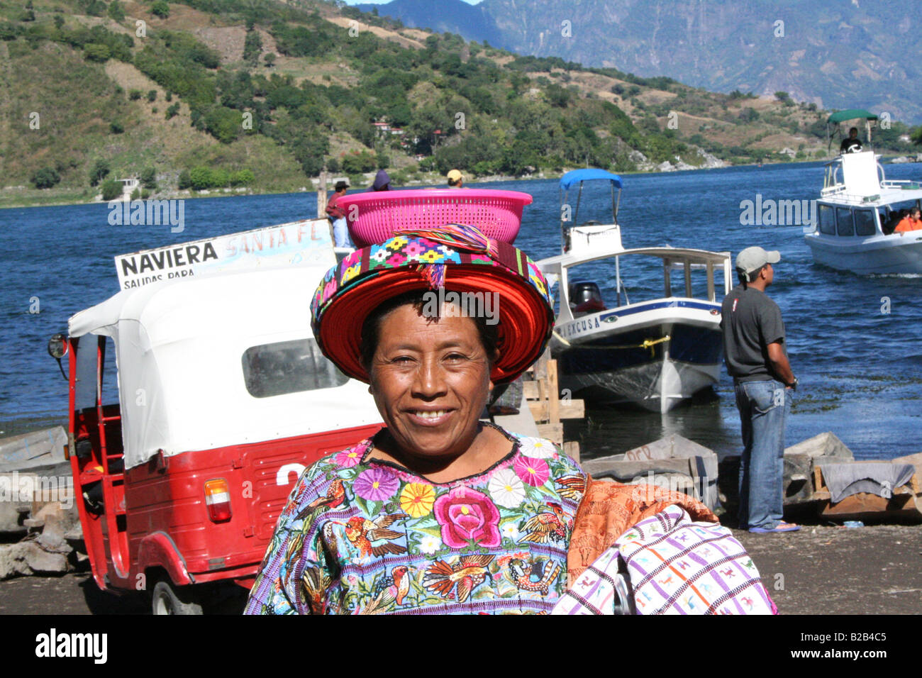 Eine Frau mit einem Korb auf dem Kopf, Verkauf von Stoffen an den Ufern des Atitlan in Santiago im Hochland von Guatemala Stockfoto