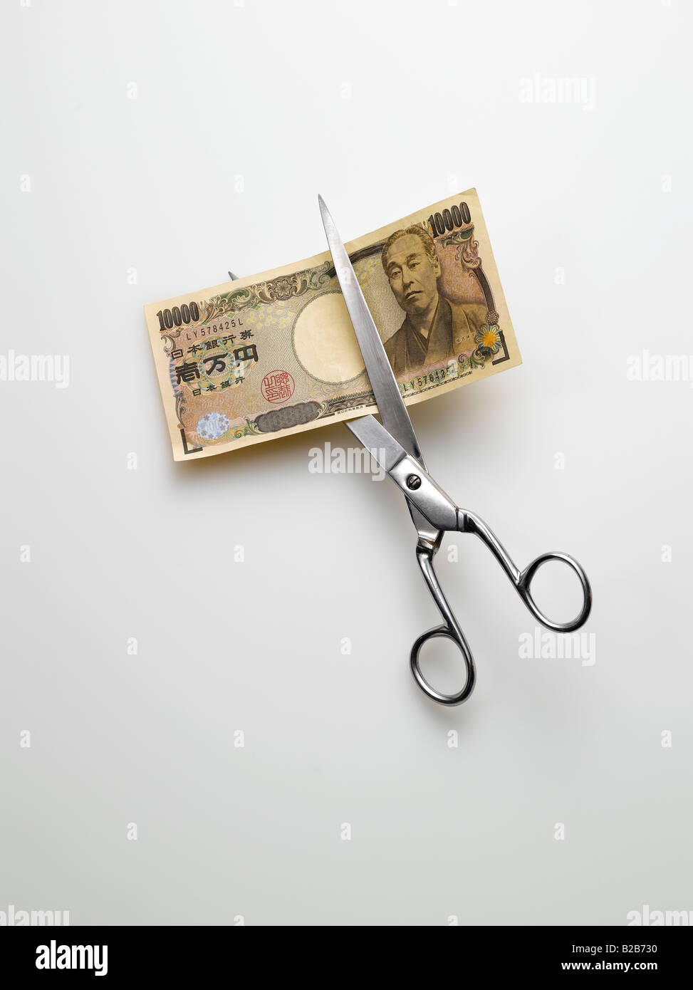 Schere schneiden japanische Yen Geld auf weißem Hintergrund Stockfoto