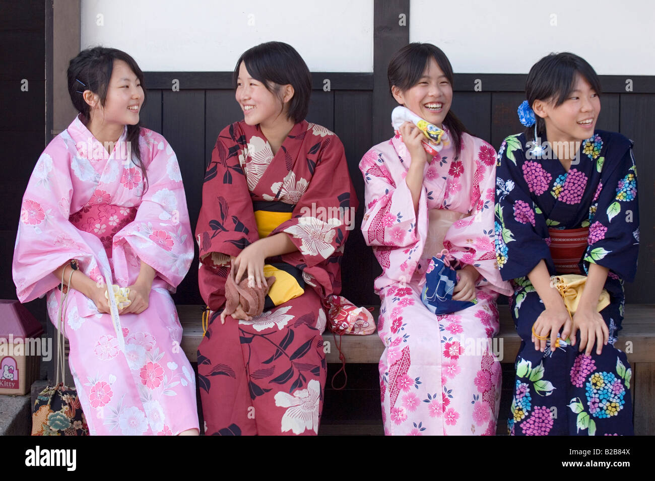 Vier Mädchen in bunte Baumwolle Yukata-Roben eine Pause in der warmen sommerlichen Hitze bei einem lokalen Kleinstadt-festival Stockfoto