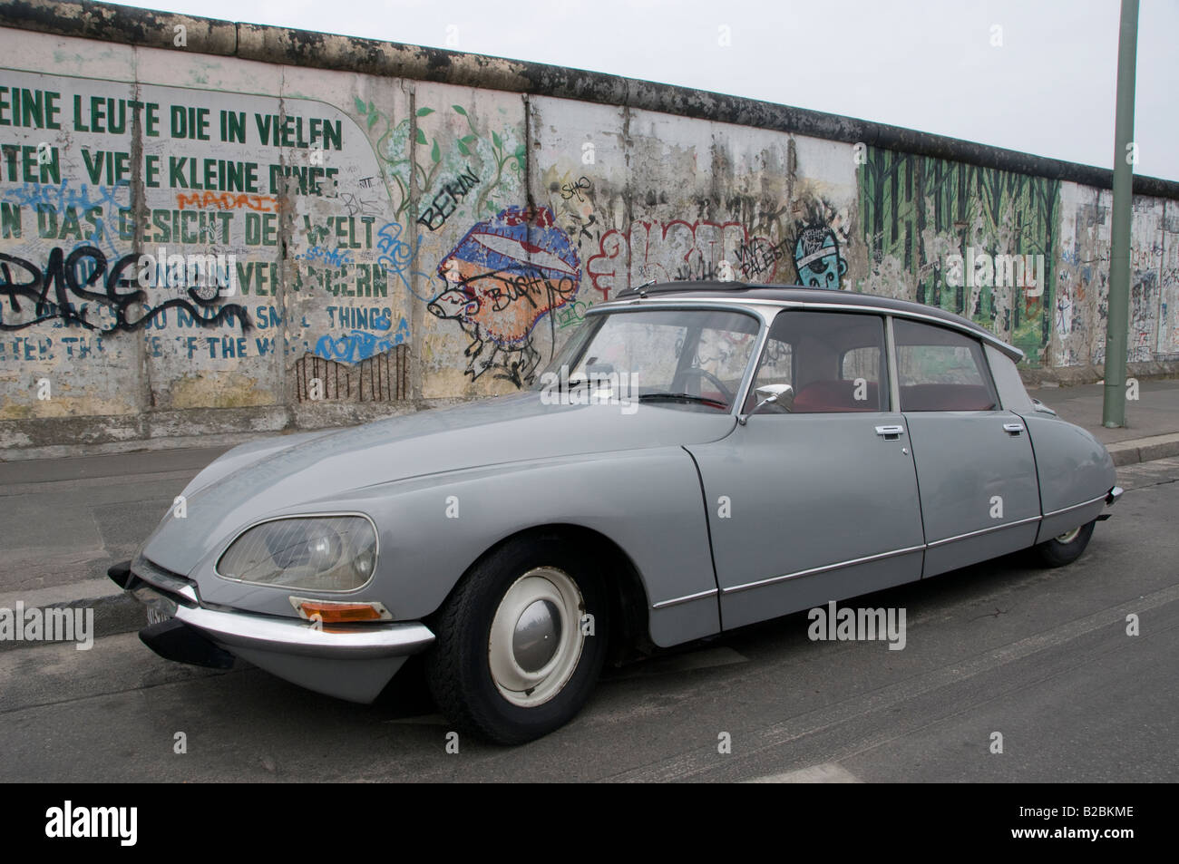 Ein altes Fahrzeug des neuen Autos, das neben der Gedenkstätte der East Side Gallery auf dem verbleibenden Teil der Berliner Mauer geparkt ist. Deutschland Stockfoto