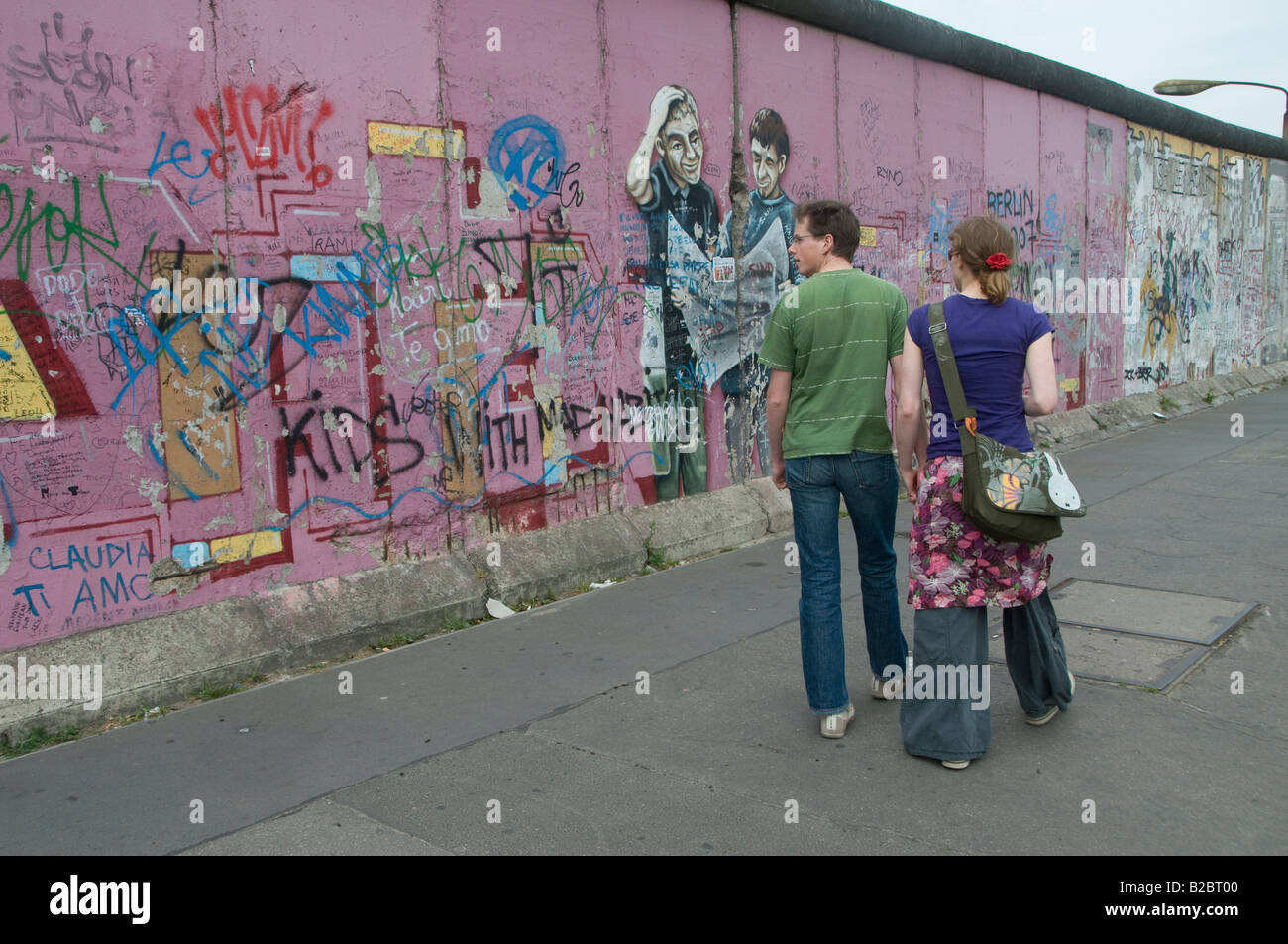 Fußgänger kommen an der Gedenkstätte der East Side Gallery auf dem verbleibenden Teil der Berliner Mauer vorbei. Deutschland Stockfoto