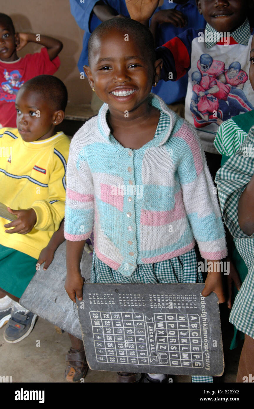 Ein Mädchen mit einem Alphabet-Brett in einer einfachen Tagespflege-Einrichtung in Akropong-Akwapim, Region Ost, Republik von Ghana, Westafrika Stockfoto