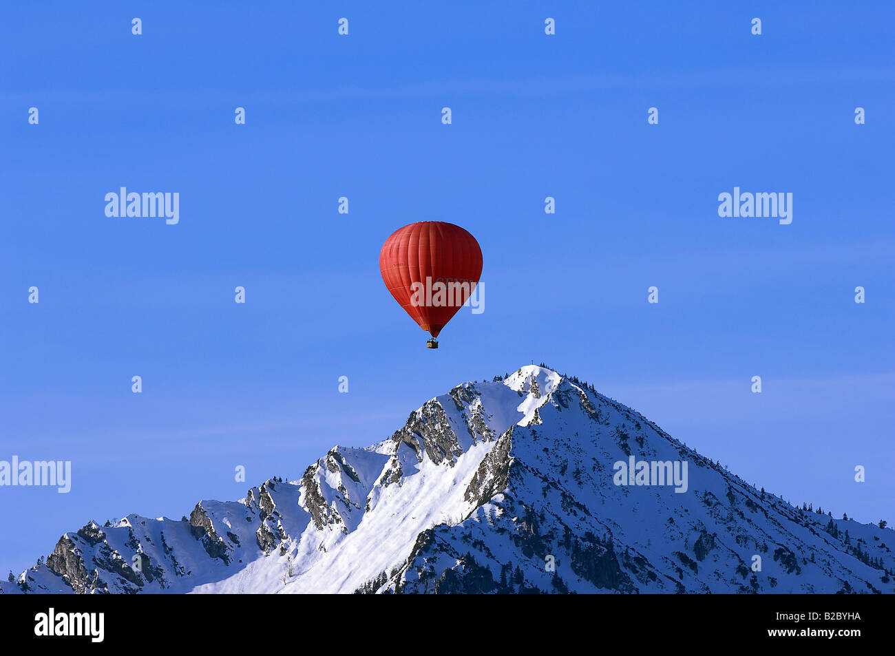 Roten Heißluftballon schwebt über den Gipfel des Mt. Ochsenkamp, Montgolfiade, Tegernseer Berge, Bad Wiessee, Bayern Stockfoto
