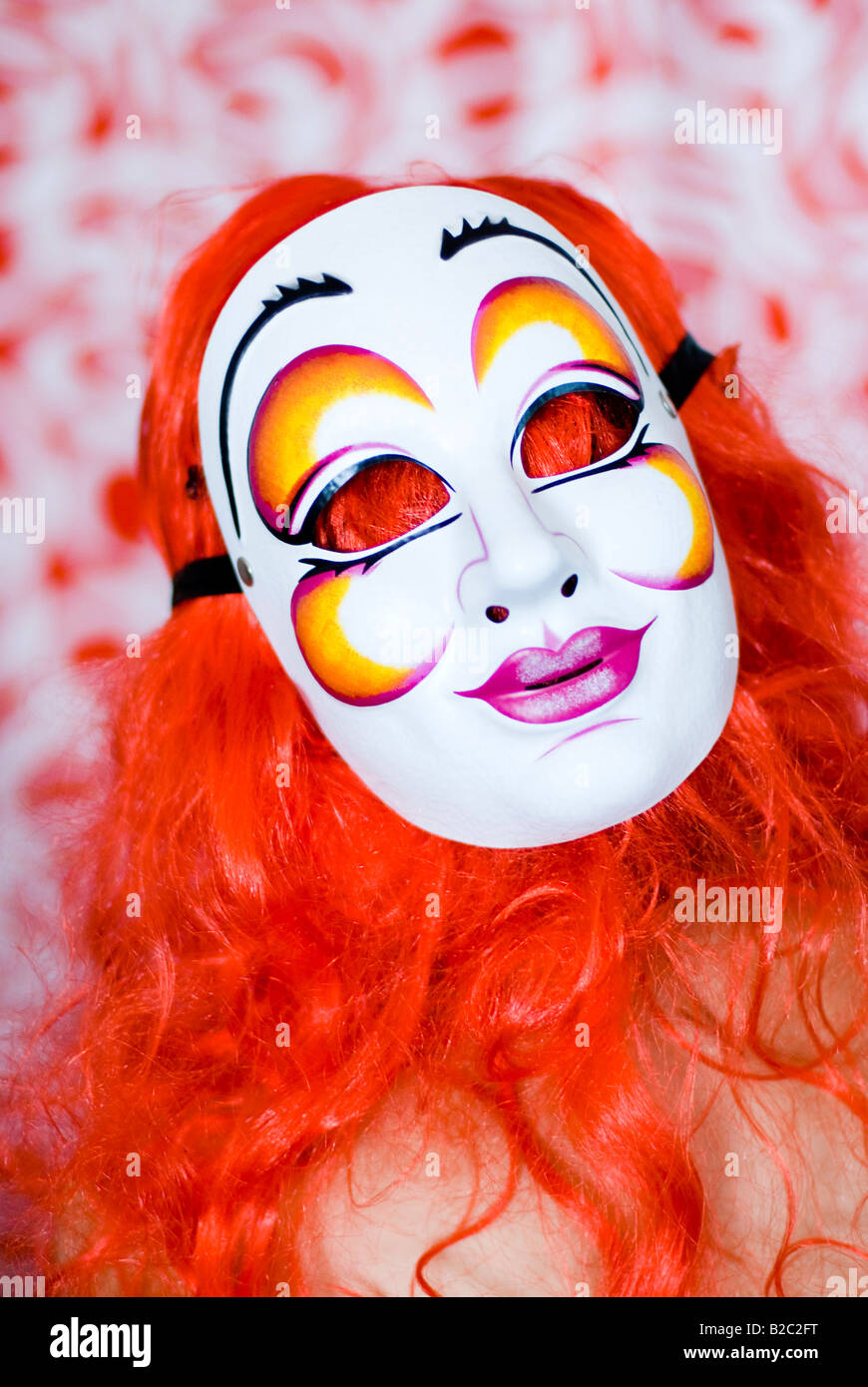 herrsche eine Frau mit einer roten Perücke und Karneval Maske Stockfoto