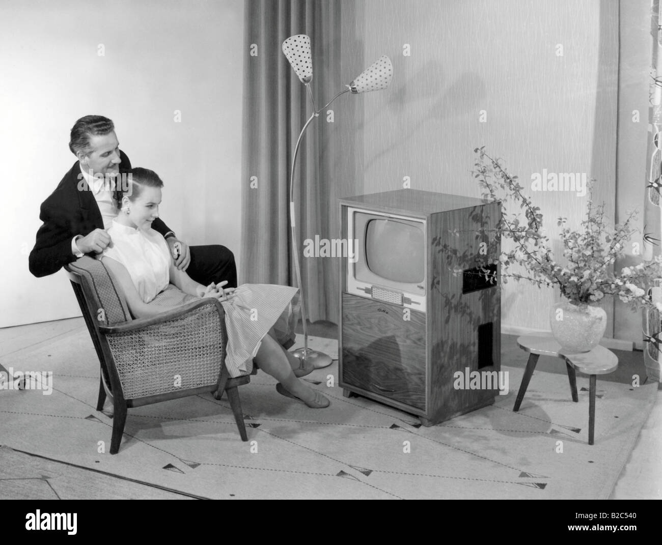 Mann und Frau sitzt auf einem Sessel vor einem Fernseher, historische Bild von ca. 1955 Stockfoto