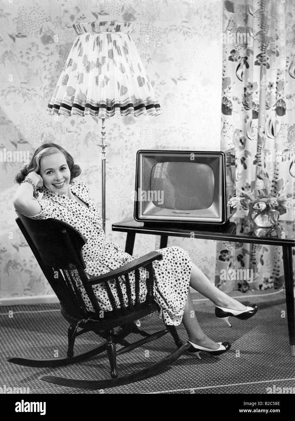 Frau sitzt vor einem Fernseher in einem Schaukelstuhl, historisches Foto, ca. 1955 Stockfoto