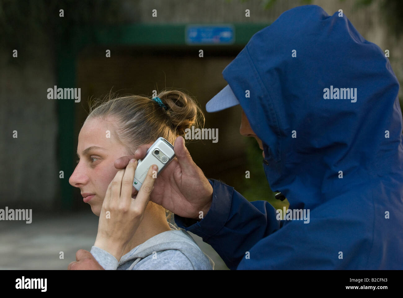 Weißen männlichen Angreifer Tassen junge weiße weibliche Opfer von ihrem Handy Stockfoto