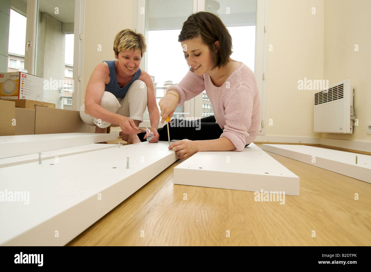 Umzug - Mutter und Tochter Möbel zusammenbauen in einem neuen Haus innen Stockfoto