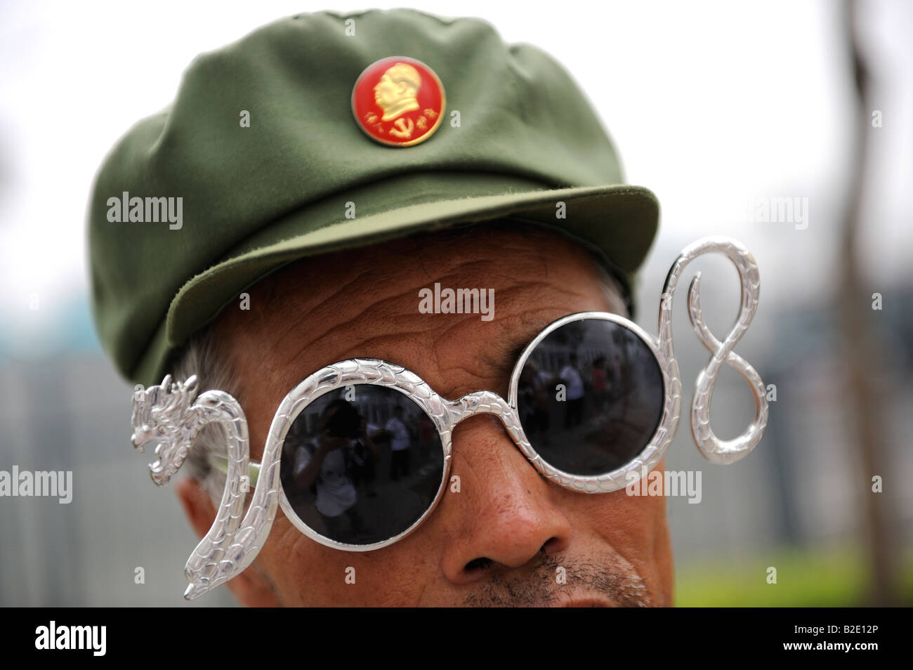 Chinesische Fan mit Mao Abzeichen und Brillen 2008 Gestaltung und Drachen außerhalb der Olympic Green in Peking. 27. Juli 2008 Stockfoto