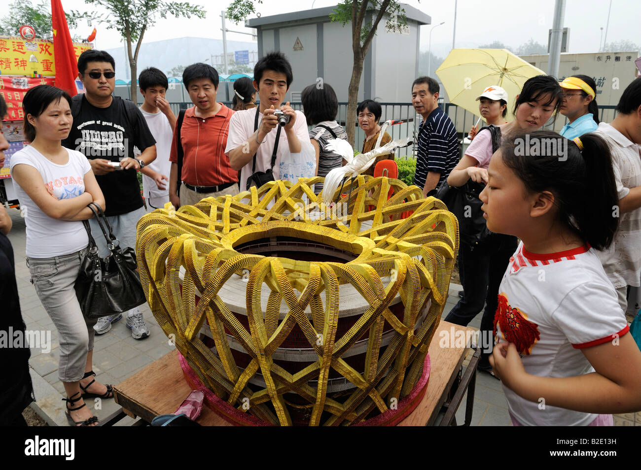 Chinesische Leute betrachten eine Papier-Nachbildung des National Stadium außerhalb der Olympic Green in Peking. 27. Juli 2008 Stockfoto