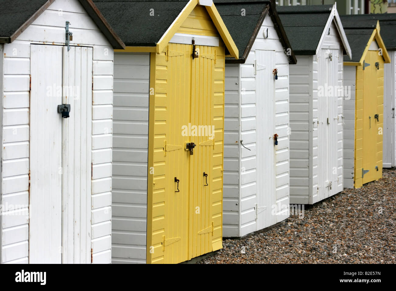 Reihe von gelben und weißen Strandhütten auf der Promenade am Seaton, Devon, England Stockfoto