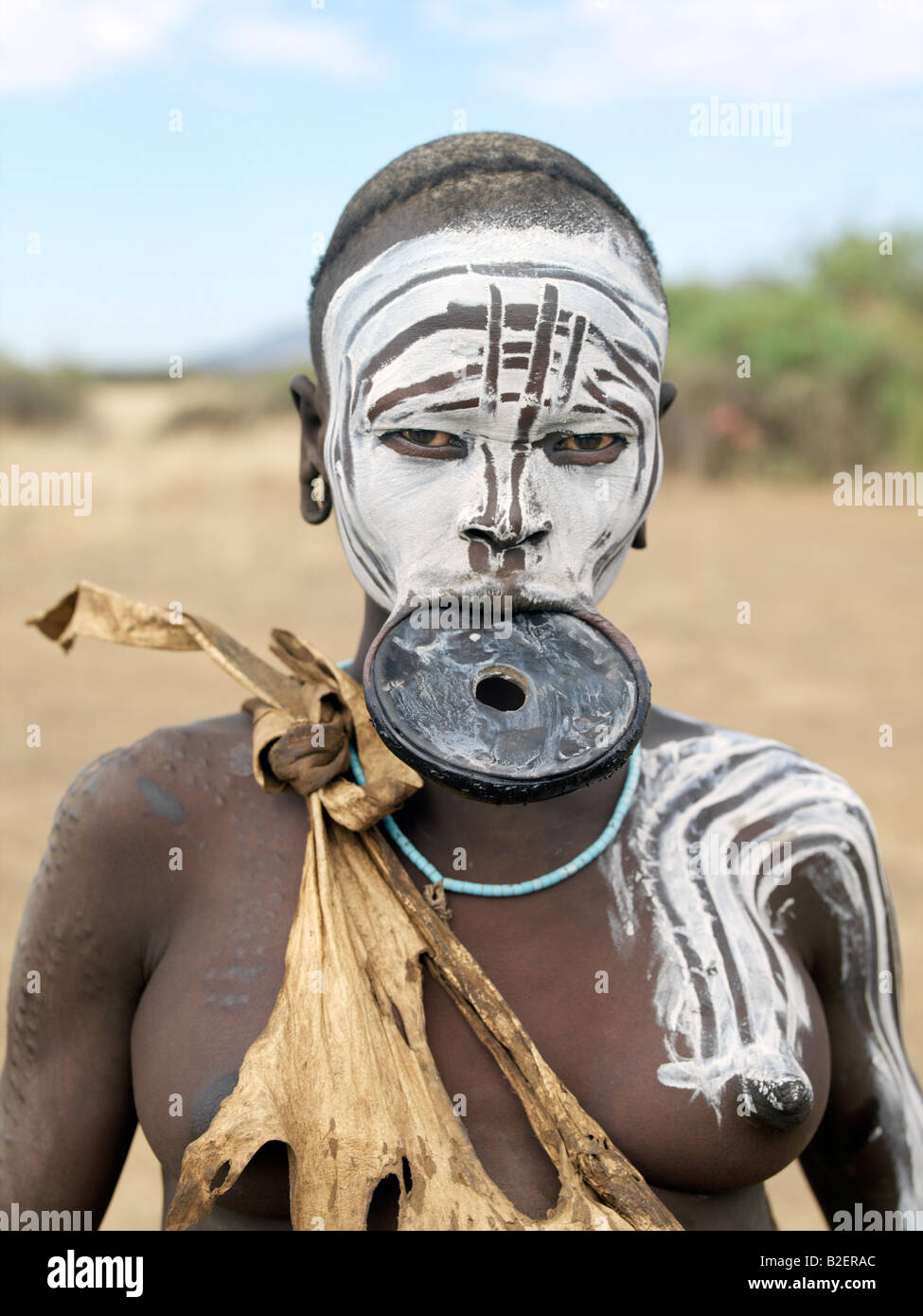 Eine Mursi-Frau mit dekorierten Gesicht und Körper Scarification trägt einen großen Ton Mundlochplatte. Stockfoto