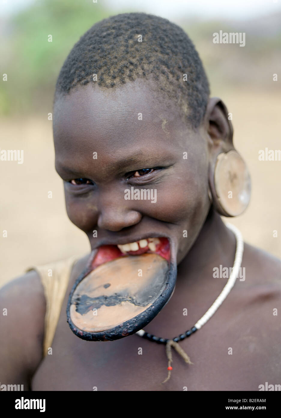 Eine Mursi-Frau trägt eine großen Ton Lippe Platte und Ohr Ornamente zu entsprechen. Stockfoto