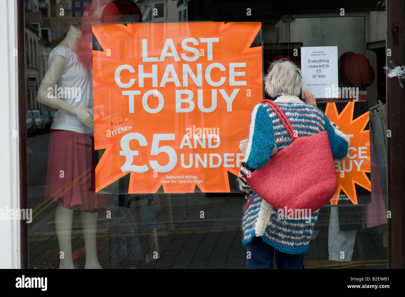 Frau auf der Suche in einem Schaufenster endlich einige Schnäppchen Angebote bei £5 oder weniger Kleidung shop Verkauf Aberystwyth Wales UK Schließung Stockfoto