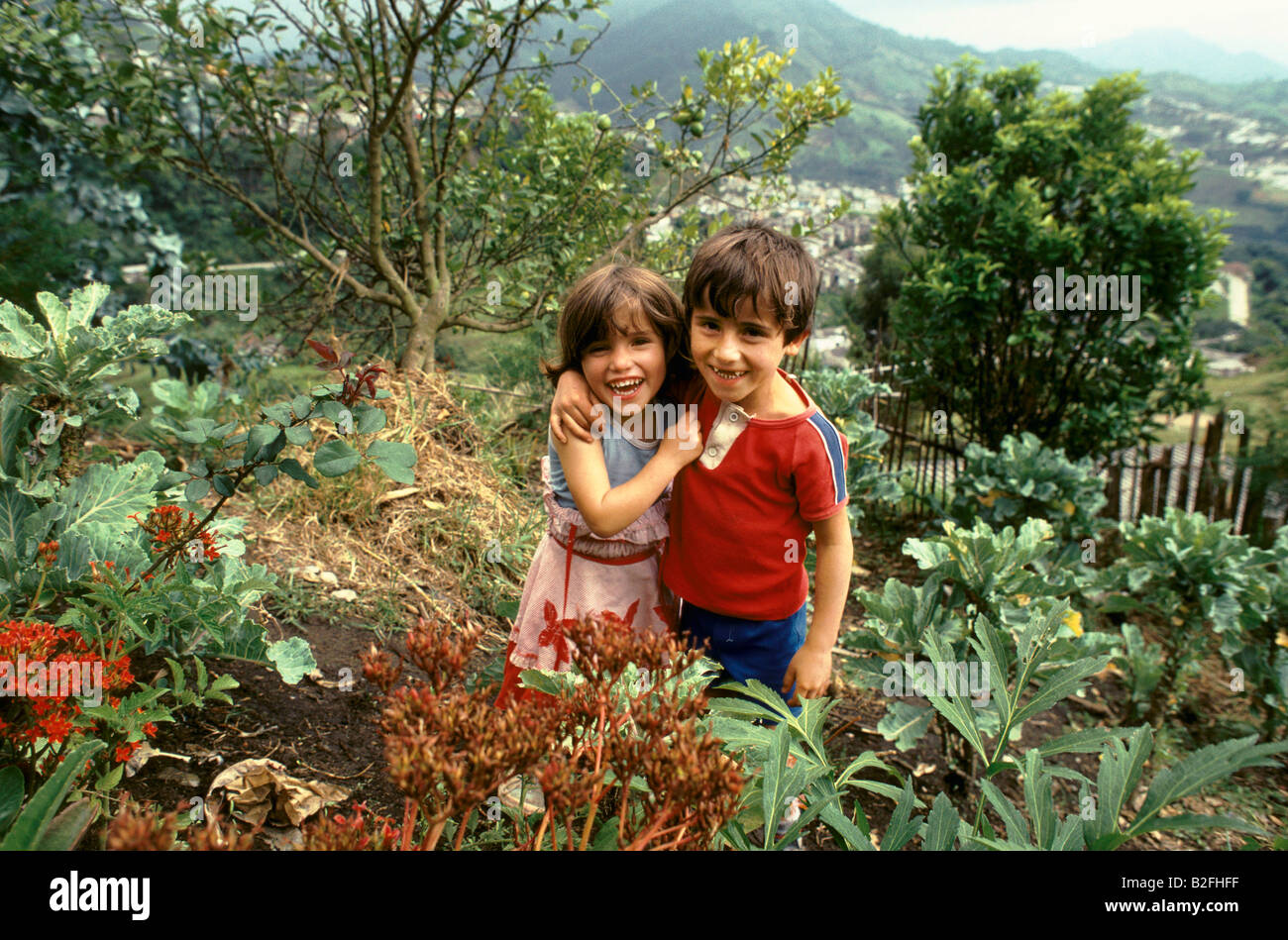 zwei lächelnde Kinder Ninos de Los Andes-Stiftung stehen im Garten Stockfoto
