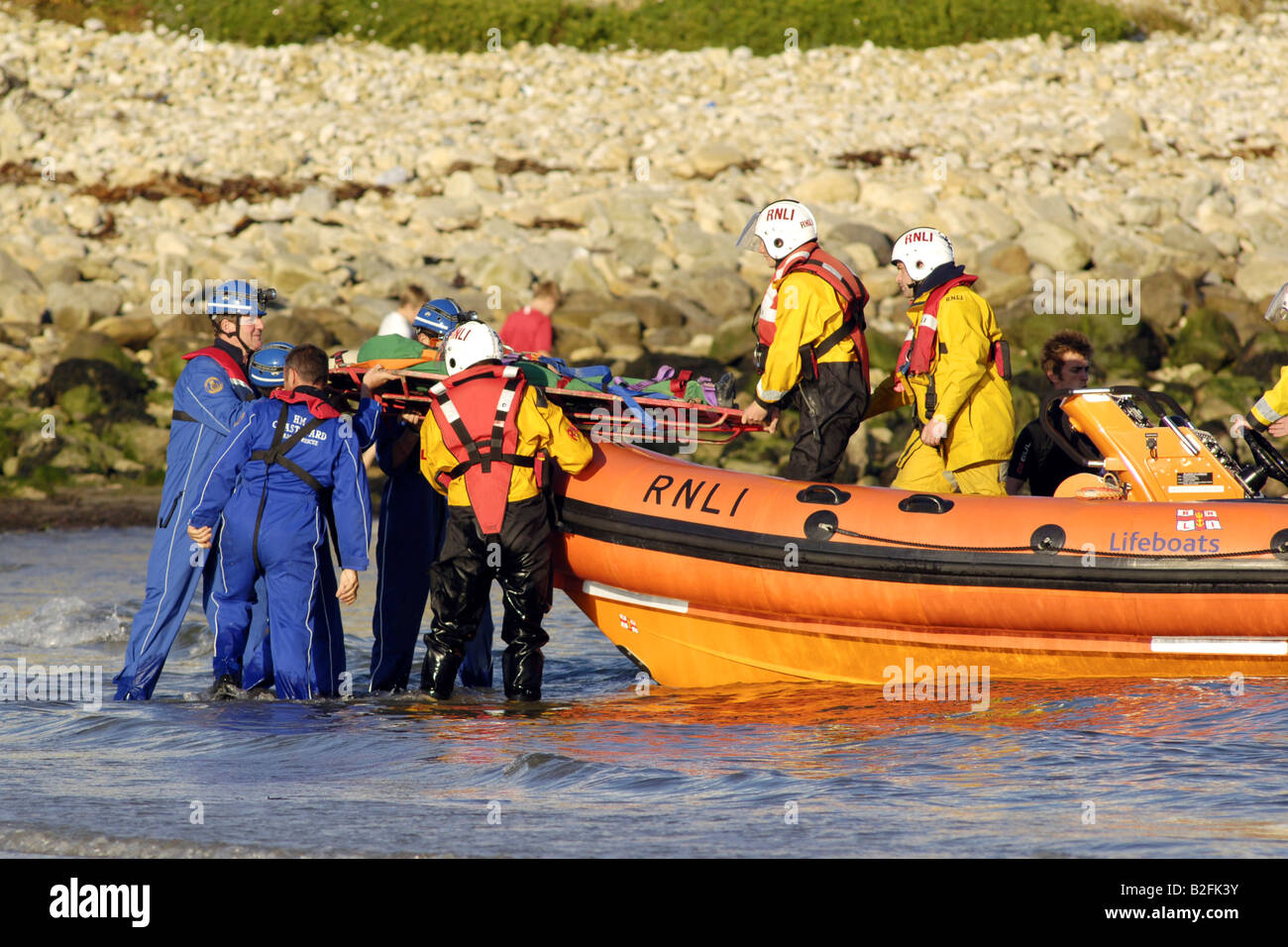 Küstenwache am Ufer Rettung Freiwilligen in seinem blauen Overalls heben einen Körper auf einem Rettungsboot warten Stockfoto