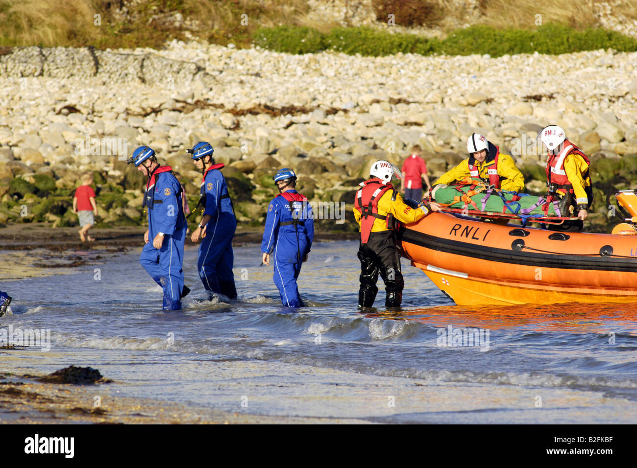Küstenwache am Ufer Rettung Freiwilligen in seinem blauen Overalls heben einen Körper auf einem Rettungsboot warten Stockfoto